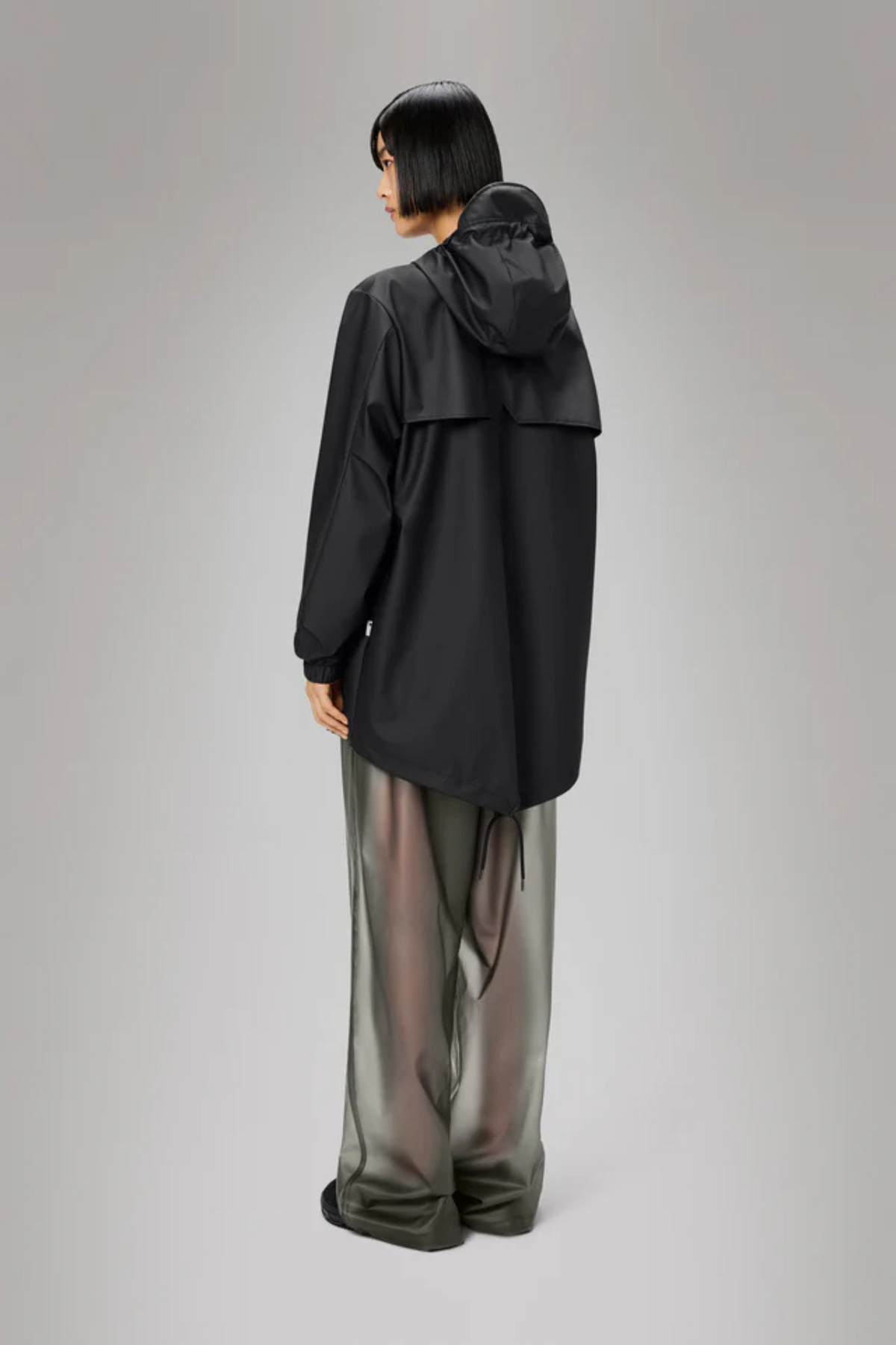 Model wearing the Rains fishtail jacket W3 in black. Back view