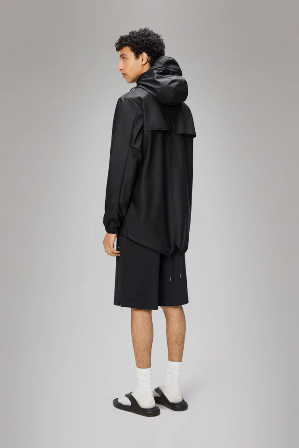 Model wearing the Rains fishtail jacket W3 in black. Back view